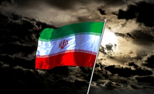 The Iranian national flag flying against a dark, cloudy sky. The Iranian national flag flying against a dark, cloudy sky.