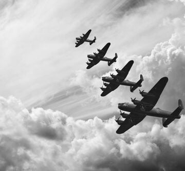 A formation of Avro Lancaster bombers flying through a cloudy sky, a scene often associated with World War II. A formation of Avro Lancaster bombers flying through a cloudy sky, a scene often associated with World War II.