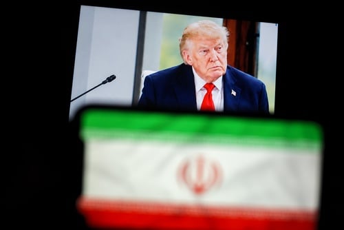 Donald Trump at a podium with a blurred image of the flag of Iran in the foreground. Donald Trump at a podium with a blurred image of the flag of Iran in the foreground.