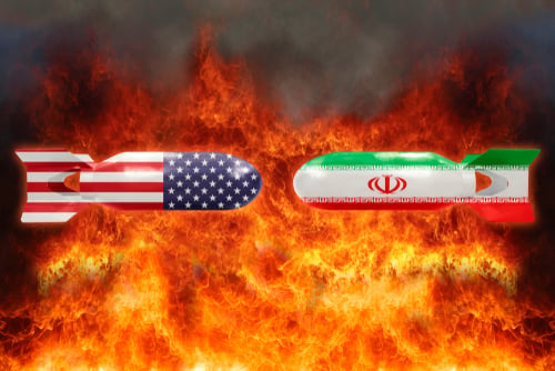 A digital illustration depicting two opposing missile or bomb shapes draped in the national flags of the United States and Iran, set against a fiery background. A digital illustration depicting two opposing missile or bomb shapes draped in the national flags of the United States and Iran, set against a fiery background.