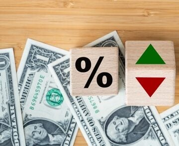 A percentage block alongside directional arrows sits atop U.S. dollar bills, representing the ongoing movement of lending costs and investment yields. A percentage block alongside directional arrows sits atop U.S. dollar bills, representing the ongoing movement of lending costs and investment yields.