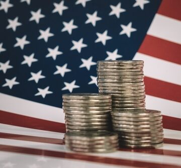 Stacks of U.S. coins in front of an American Flag.