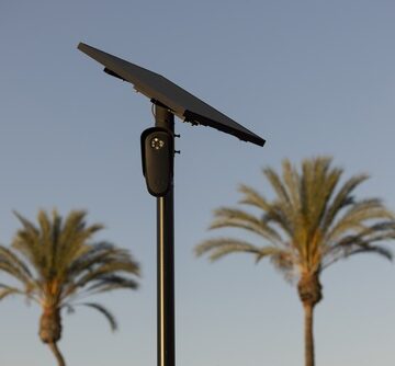 A solar-powered Flock Safety automated license plate reading (ALPR) camera mounted on a pole against a clear sky.