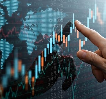 A hand points at a digital financial candlestick chart overlaying a world map. A hand points at a digital financial candlestick chart overlaying a world map.