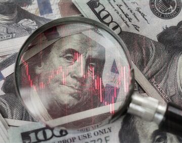 A close-up of U.S. $100 dollar bills viewed through a magnifying glass with a red downward trend chart overlaid, symbolizing economic decline or financial risk. A close-up of U.S. $100 dollar bills viewed through a magnifying glass with a red downward trend chart overlaid, symbolizing economic decline or financial risk.