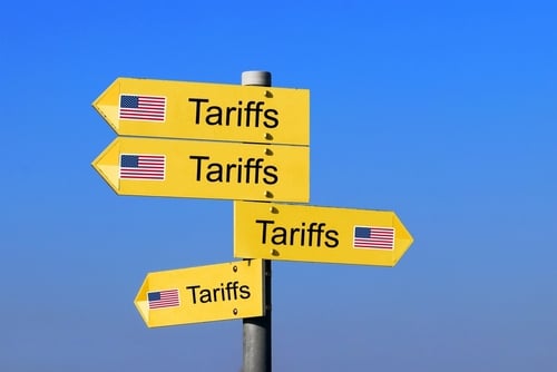 Yellow directional road signs with the word "Tariffs" and U.S. flags pointing in various ways.
