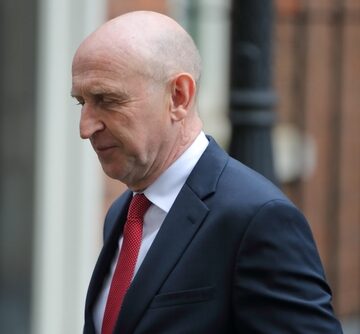 British politician John Healey wears a dark suit and a red tie while leaving No. 10 Downing Street in London. British politician John Healey wears a dark suit and a red tie while leaving No. 10 Downing Street in London.