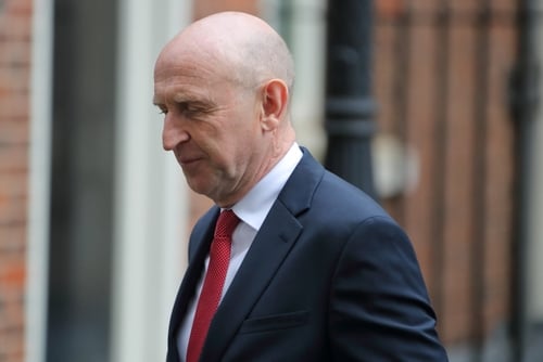 British politician John Healey wears a dark suit and a red tie while leaving No. 10 Downing Street in London.