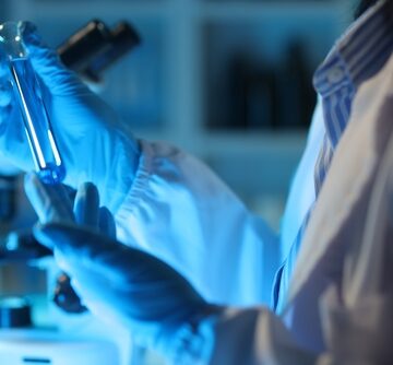 Medical,Scientist,Analyzing,Test,Tube,With,Blue,Liquid,In,Laboratory. NANOPARTICLES MAY OFFER AN ALZHEIMER’S CURE