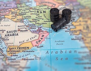 A conceptual map of the Middle East with miniature oil barrels placed over the region near the Strait of Hormuz.