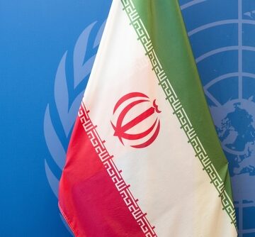 The national flag of Iran displayed in front of the United Nations emblem. The national flag of Iran displayed in front of the United Nations emblem.