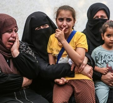 A group of grieving Palestinian women and children with some appearing visibly distressed and crying. A group of grieving Palestinian women and children with some appearing visibly distressed and crying.