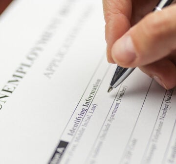 Close-up view of a person filling out an application form for unemployment benefits. Close-up view of a person filling out an application form for unemployment benefits.
