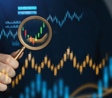 Concept image shows a person using a magnifying glass to examine a financial candlestick chart. Concept image shows a person using a magnifying glass to examine a financial candlestick chart.