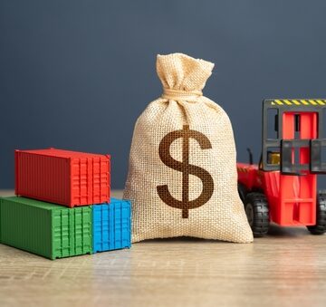 Concept image of the financial impact of global logistics, import costs, and tariffs on international trade illustrated with cargo containers, a money bag, and a forklift. Concept image of the financial impact of global logistics, import costs, and tariffs on international trade illustrated with cargo containers, a money bag, and a forklift.