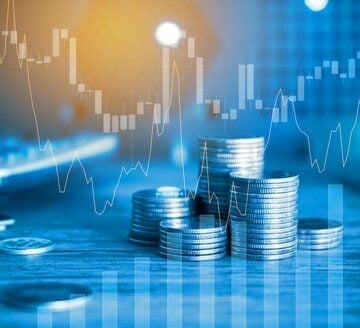 Finance and business concept, highlighting investment graphs overlaid with coin stacks on a table. Finance and business concept, highlighting investment graphs overlaid with coin stacks on a table.