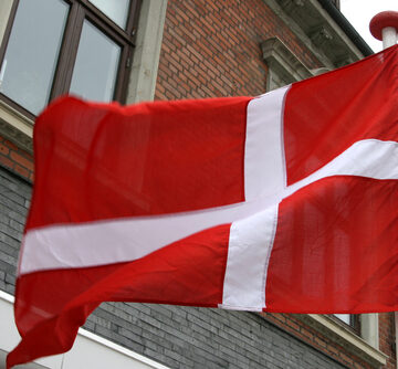 The national flag of Denmark, known as the Dannebrog, featuring a white Scandinavian cross on a red background. The national flag of Denmark, known as the Dannebrog, featuring a white Scandinavian cross on a red background.