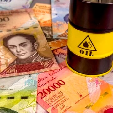 Concept image of Venezuelan bolívar banknotes arranged alongside a miniature oil barrel. Concept image of Venezuelan bolívar banknotes arranged alongside a miniature oil barrel.