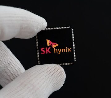 A gloved hand holds a semiconductor memory chip featuring the corporate logo of the South Korean chipmaker SK Hynix. A gloved hand holds a semiconductor memory chip featuring the corporate logo of the South Korean chipmaker SK Hynix.
