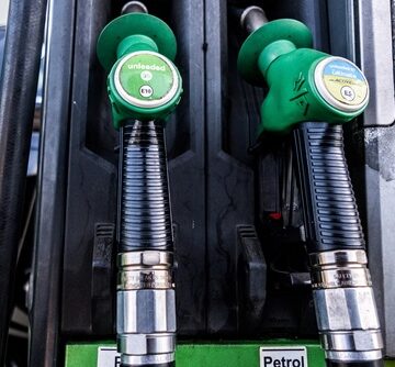 Green fuel pump nozzles and handles labeled for petrol at a service station. Green fuel pump nozzles and handles labeled for petrol at a service station.