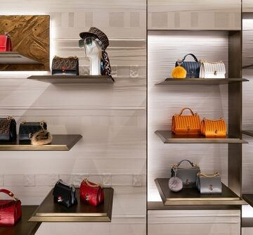 A luxury handbag and accessory display featuring structured leather bags – including Fendi-style designs – arranged on illuminated shelves. A luxury handbag and accessory display featuring structured leather bags – including Fendi-style designs – arranged on illuminated shelves.