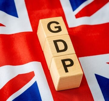 Wooden blocks spelling GDP (Gross Domestic Product) placed on top of a British Union Jack flag.