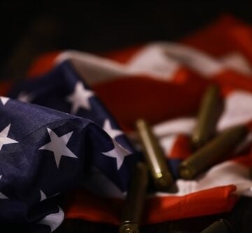 American,Flag,With,Bullet,Casings:,Symbolizing,Patriotism,And,Gun,Violence AMERICA’S DEADLY ADDICTION TO WAR