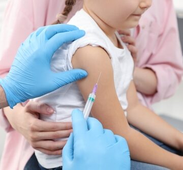 A young child is receiving an injection, commonly an immunization or vaccination, in the upper arm administered by a healthcare professional wearing blue gloves. A young child is receiving an injection, commonly an immunization or vaccination, in the upper arm administered by a healthcare professional wearing blue gloves.