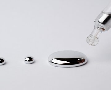 The image shows liquid mercury (also known as quicksilver, with the chemical symbol Hg), a dense, silvery-white metallic element that remains liquid at room temperature.
