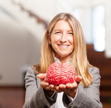 A smiling woman holding a red model of a human brain in her hands. A smiling woman holding a red model of a human brain in her hands.