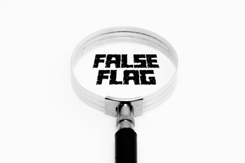 A magnifying glass focused on the text "FALSE FLAG." A magnifying glass focused on the text "FALSE FLAG."