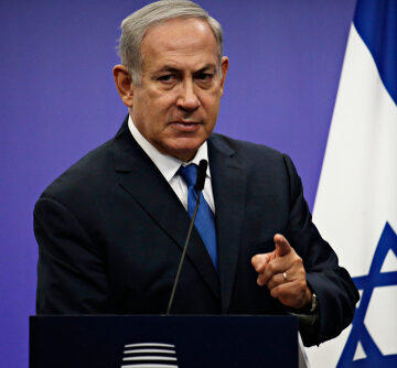 Israeli Prime Minister Benjamin Netanyahu at a press conference podium.