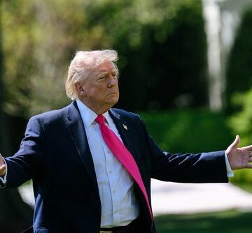 Donald Trump, with arms spread, speaks with members of the media on the South Lawn of the White House.