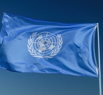 The flag of the United Nations, which features a white official emblem centered on a light blue background. The flag of the United Nations, which features a white official emblem centered on a light blue background.