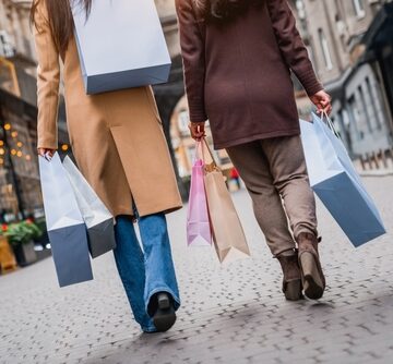 Two people walking down a city street while carrying various shopping bags. Two people walking down a city street while carrying various shopping bags.